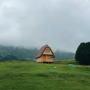 Cabane en bois isolée sur une prairie verdoyante dans les montagnes du Jura, sous un ciel nuageux