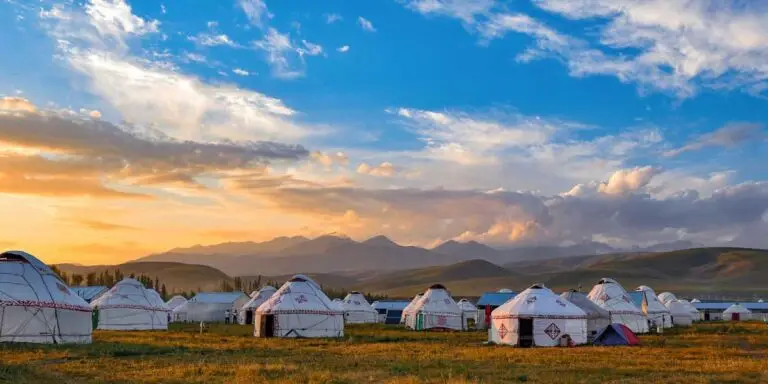 Plusieurs yourtes au soleil couchant avec des montagne à perte de vue